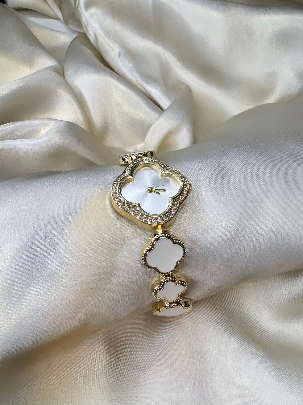 Clover watch white White clover-shaped watch with gold-tone finish and adjustable bracelet.